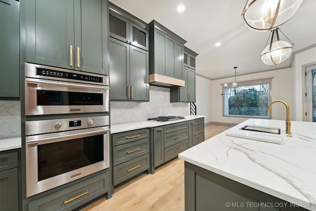 kitchen featuring appliances with stainless steel finishes, light hardwood / wood-style floors, pendant lighting, crown molding, and decorative backsplash