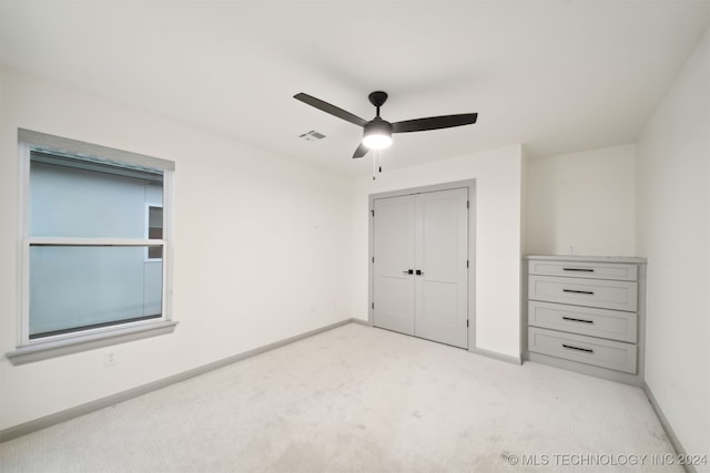 unfurnished bedroom with a closet, ceiling fan, and light colored carpet