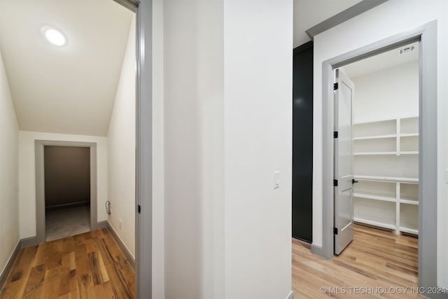 hallway with hardwood / wood-style floors and vaulted ceiling