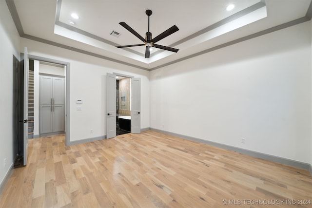 unfurnished bedroom with ornamental molding, ceiling fan, light wood-type flooring, and a raised ceiling