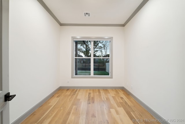 spare room with ornamental molding and wood-type flooring