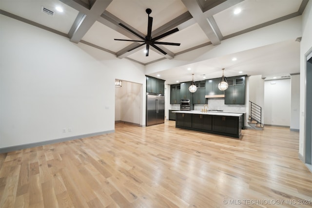 kitchen with pendant lighting, light hardwood / wood-style floors, an island with sink, and stainless steel built in refrigerator