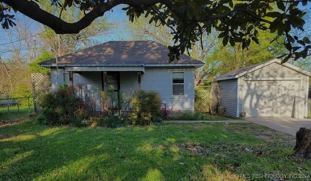 view of front of home with a garage, an outdoor structure, and a front lawn