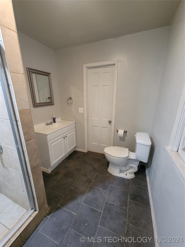 bathroom featuring vanity, toilet, and a shower with shower door