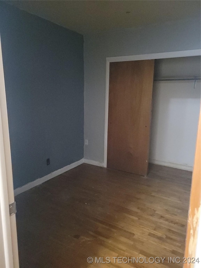 unfurnished bedroom with hardwood / wood-style floors and a closet