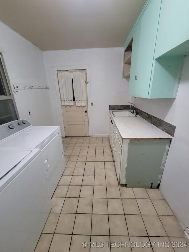 clothes washing area with cabinets, sink, washer and dryer, and light tile patterned floors