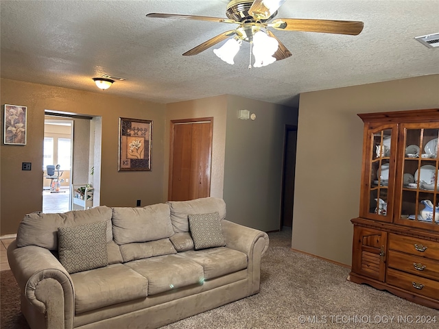 living room featuring a textured ceiling, light colored carpet, and ceiling fan