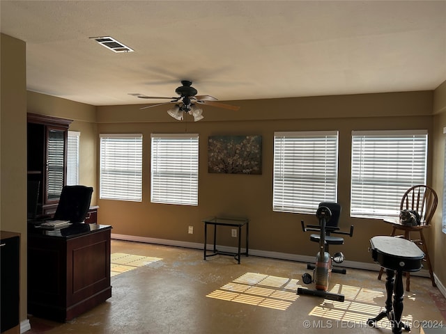 exercise room with concrete floors, a healthy amount of sunlight, and ceiling fan