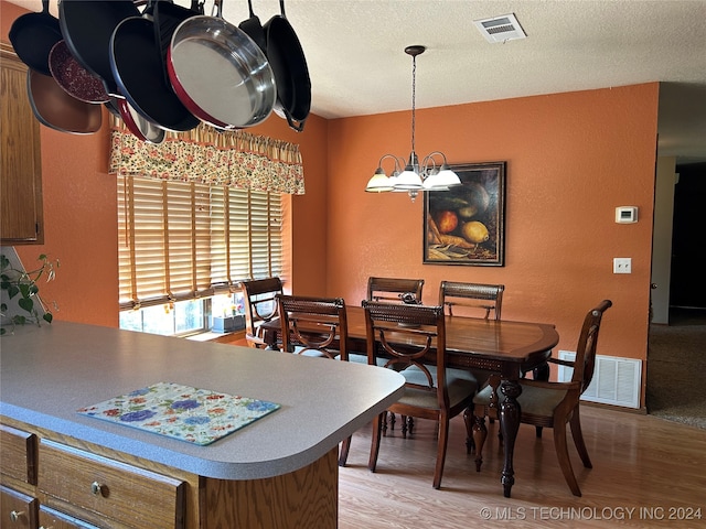 dining room with a chandelier, a textured ceiling, and light hardwood / wood-style floors