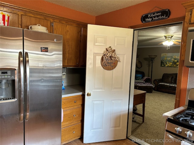 kitchen featuring appliances with stainless steel finishes, light colored carpet, a textured ceiling, and ceiling fan