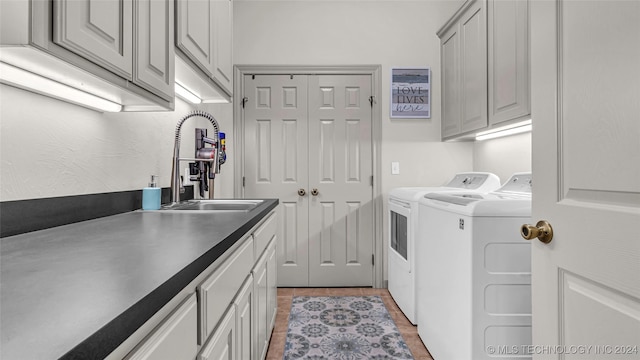 clothes washing area featuring cabinets, sink, light tile patterned floors, and washer and clothes dryer