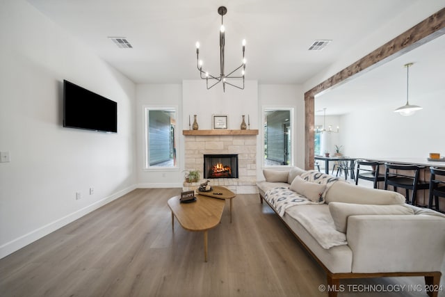 living room featuring a stone fireplace, wood-type flooring, and a healthy amount of sunlight