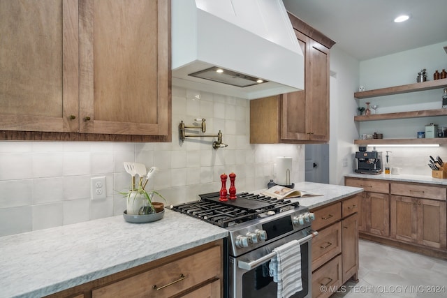 kitchen featuring stainless steel range, premium range hood, light tile patterned floors, and backsplash