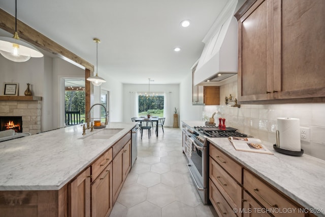 kitchen featuring appliances with stainless steel finishes, sink, hanging light fixtures, premium range hood, and a kitchen island with sink