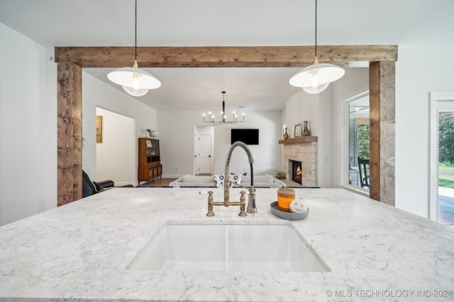 kitchen featuring light stone counters, sink, a fireplace, and decorative light fixtures