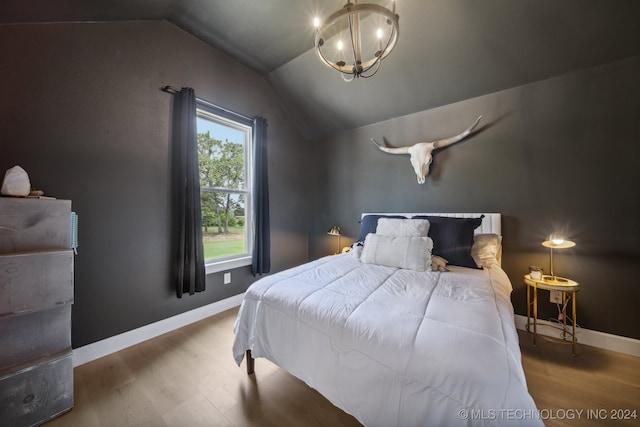 bedroom with hardwood / wood-style flooring, a chandelier, and vaulted ceiling