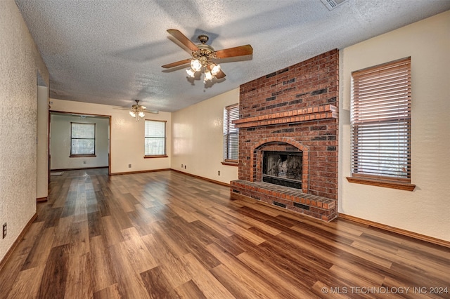 unfurnished living room with a brick fireplace, a textured ceiling, ceiling fan, and hardwood / wood-style floors