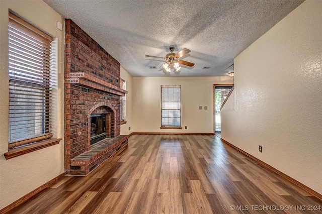 unfurnished living room featuring a fireplace, a textured ceiling, ceiling fan, and hardwood / wood-style floors