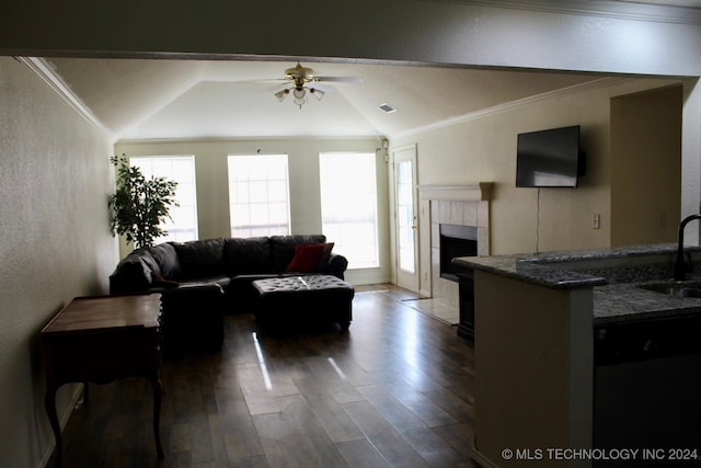 living room featuring vaulted ceiling, ceiling fan, wood-type flooring, a tiled fireplace, and sink