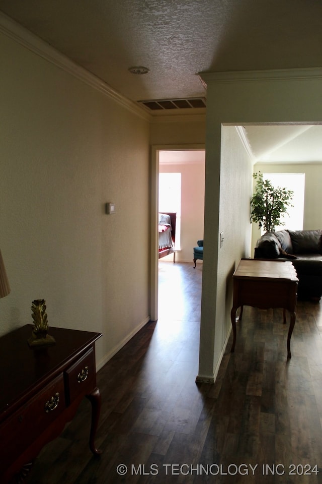 corridor with a textured ceiling, hardwood / wood-style flooring, and crown molding