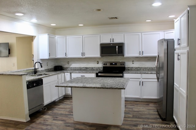 kitchen featuring appliances with stainless steel finishes, white cabinets, dark hardwood / wood-style floors, and a kitchen island