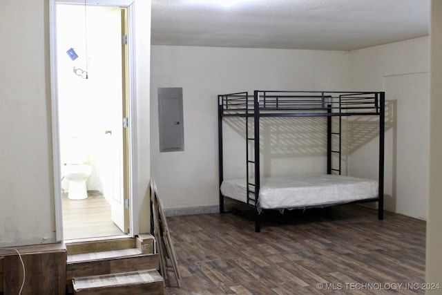 bedroom with ensuite bathroom, hardwood / wood-style floors, and electric panel