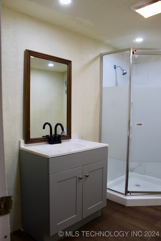 bathroom with wood-type flooring, a shower with door, and vanity