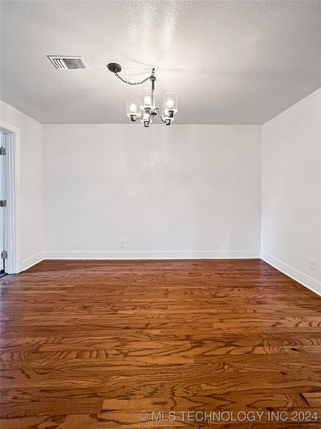 unfurnished room with wood-type flooring, a chandelier, and a textured ceiling