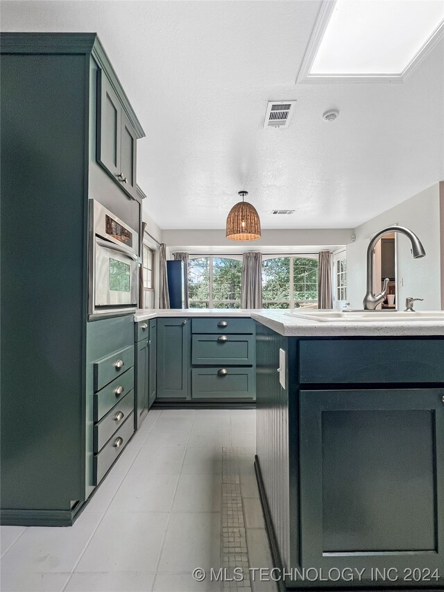 kitchen with oven, light tile patterned floors, sink, and green cabinetry