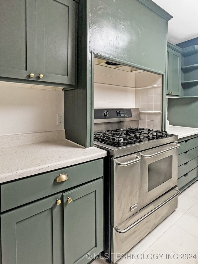 kitchen with backsplash, green cabinetry, light tile patterned floors, and stainless steel gas range oven