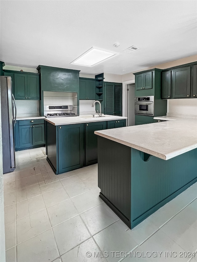 kitchen with light tile patterned floors, sink, gas range, a center island, and stainless steel refrigerator