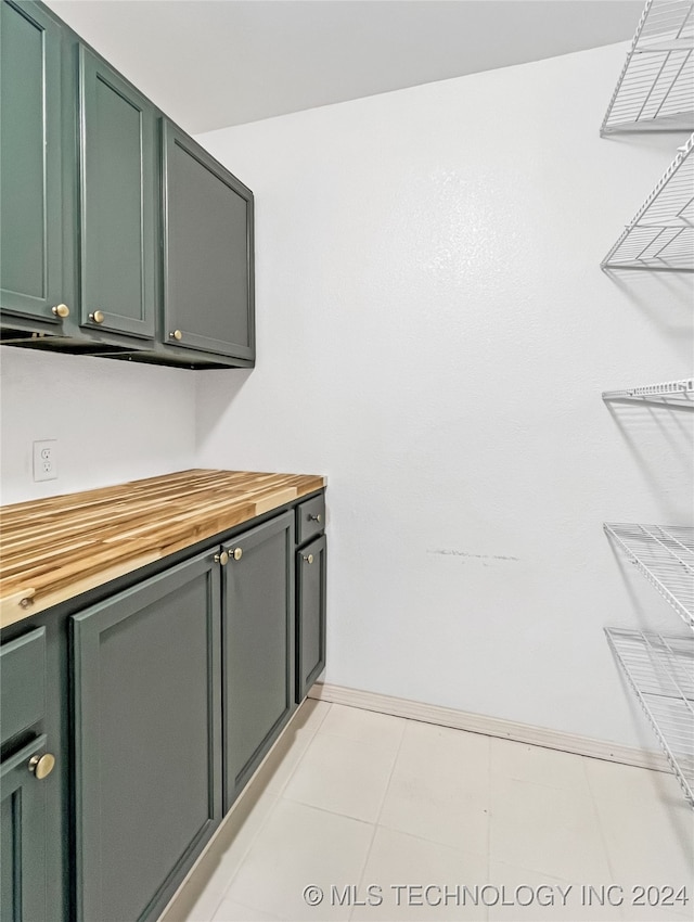 interior space featuring light tile patterned floors, wood counters, and green cabinets