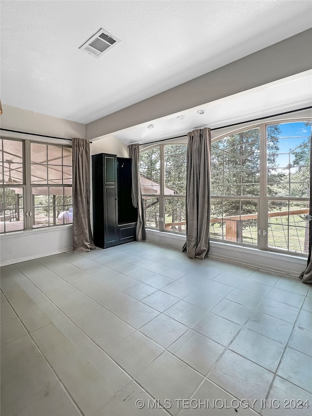 unfurnished living room with light tile patterned flooring and a wealth of natural light