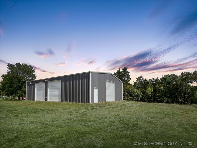 outdoor structure at dusk with a garage and a lawn