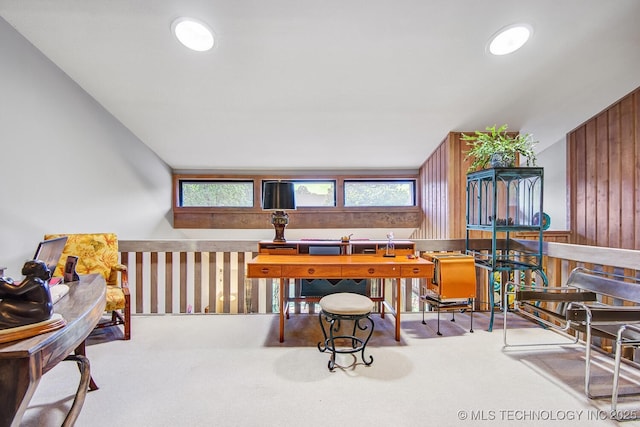 carpeted office space with a wealth of natural light, lofted ceiling, and wood walls