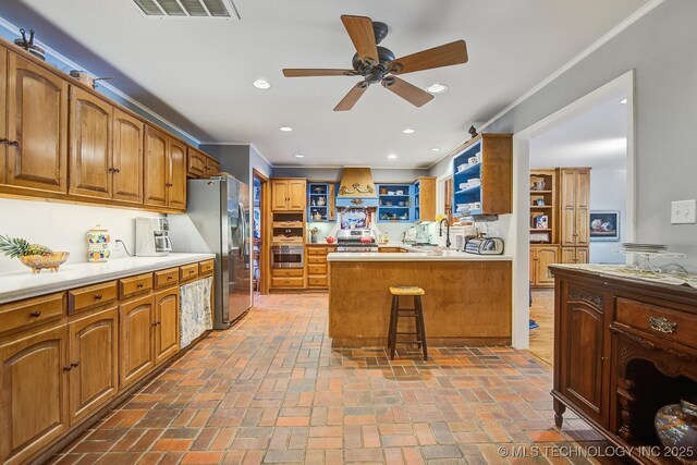 kitchen featuring a breakfast bar, custom exhaust hood, ornamental molding, appliances with stainless steel finishes, and kitchen peninsula