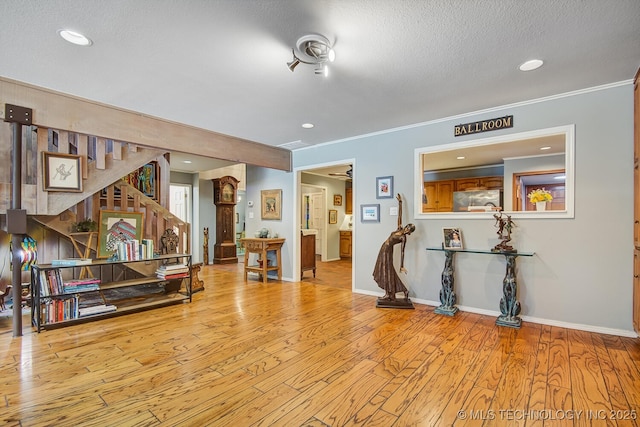 interior space featuring crown molding, a textured ceiling, and light wood-type flooring