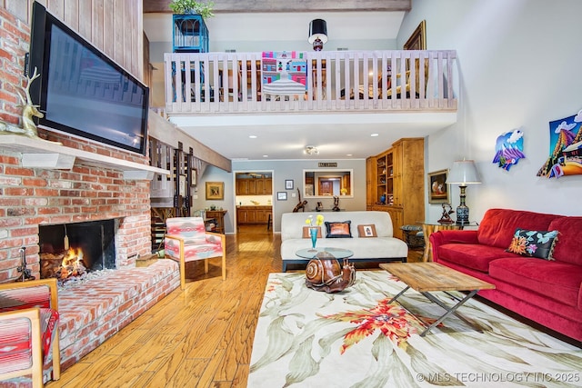 living room with a brick fireplace, wood finished floors, and a high ceiling