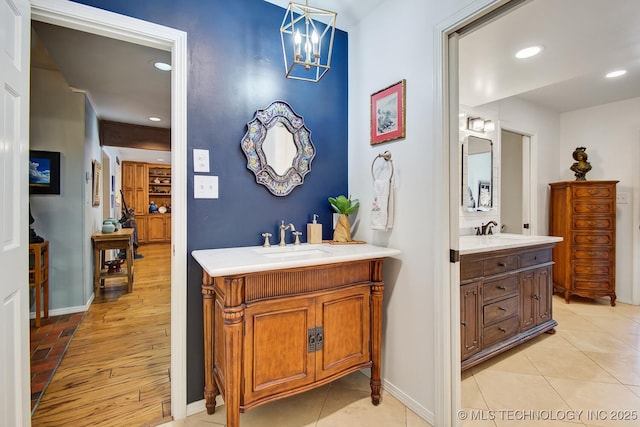 bathroom with recessed lighting, two vanities, baseboards, and a sink