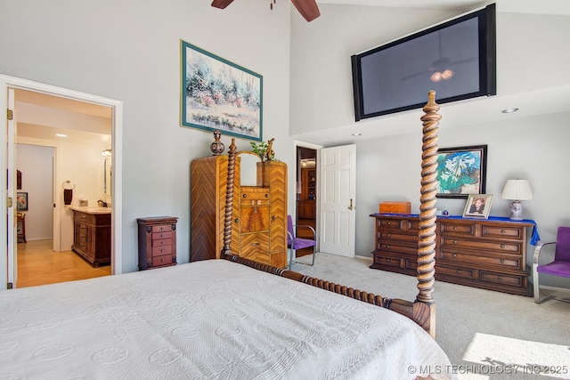 bedroom featuring ceiling fan, a towering ceiling, connected bathroom, and light carpet