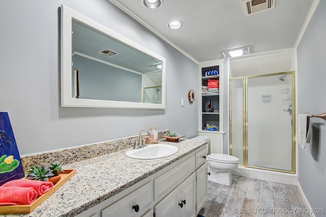 bathroom with an enclosed shower, vanity, wood-type flooring, ornamental molding, and toilet