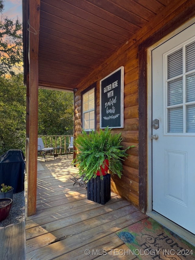 deck at dusk with a grill and covered porch