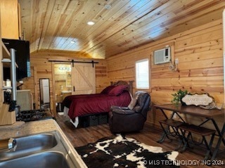 bedroom with a barn door, wood-type flooring, and wooden walls