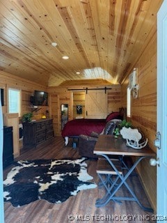 bedroom with a barn door, wooden walls, dark wood-type flooring, and wood ceiling