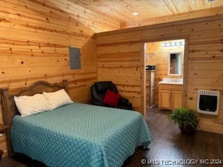 bedroom with dark hardwood / wood-style floors, heating unit, connected bathroom, electric panel, and wooden walls