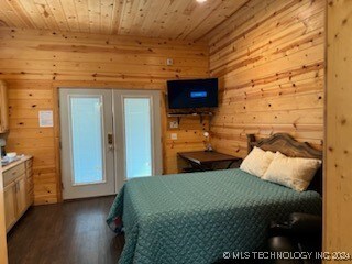 bedroom featuring wood walls, wood-type flooring, wooden ceiling, and french doors