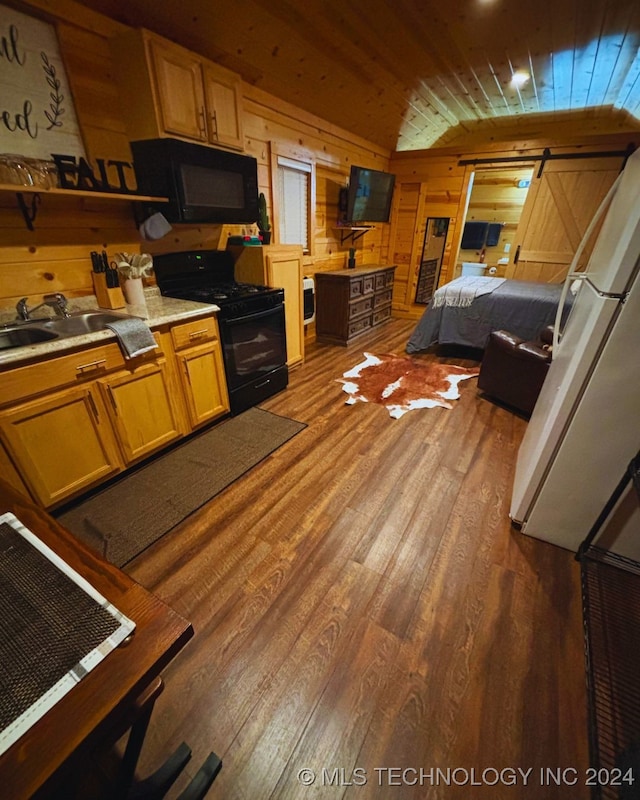 kitchen featuring black appliances, a barn door, wooden walls, hardwood / wood-style floors, and wood ceiling