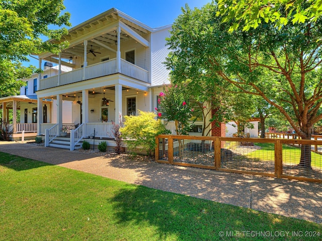 view of front facade with ceiling fan, a porch, a balcony, and a front lawn