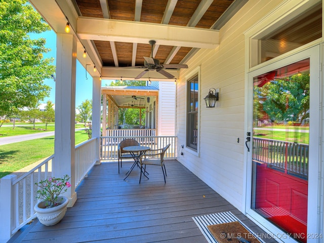 wooden terrace with covered porch, a lawn, and ceiling fan