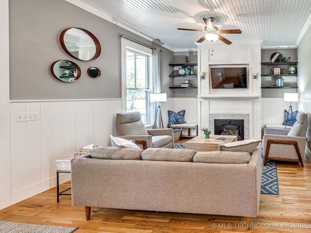 living area featuring wood ceiling, light wood-style floors, a high end fireplace, and crown molding